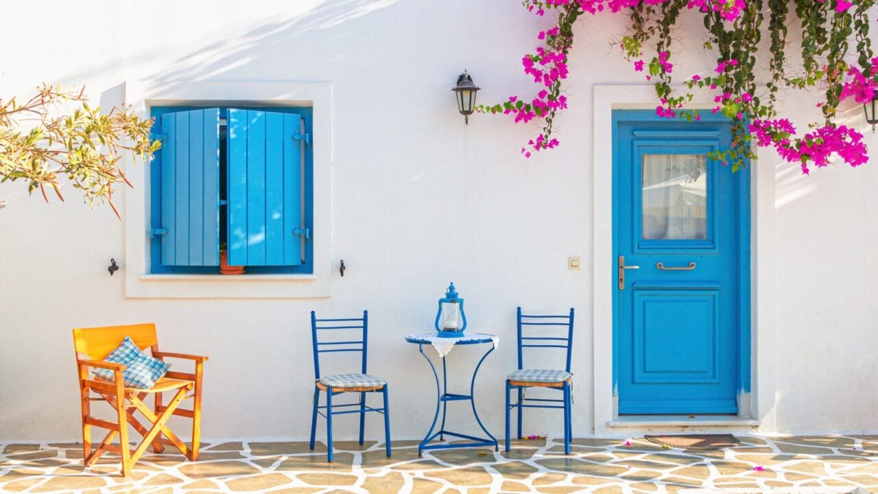 Iconic white house with blue door on a cobblestone street, one of many charming visuals during the Antiparos Greece Walking Tour with Discover Greek Culture
